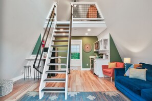 A loft-style apartment with a staircase, a kitchen, a dining area, and a living room.