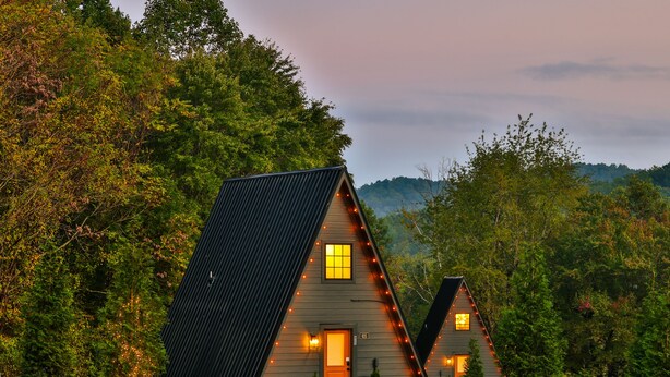 Une cabane avec un toit en pente, une porte d’entrée et une petite fenêtre.
