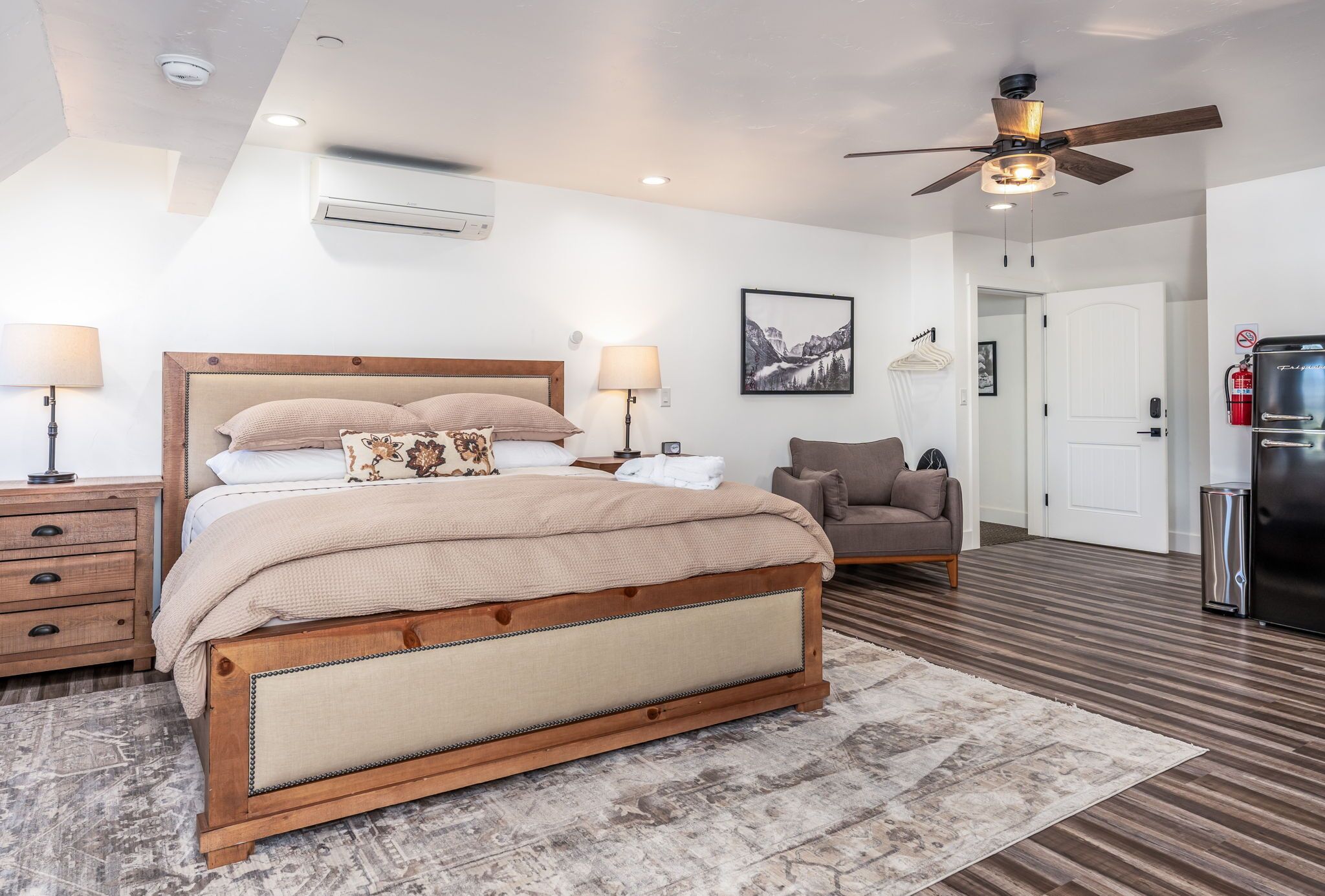 A bedroom with a wooden bed, bedside lamps, a ceiling fan, and a framed picture on the wall.