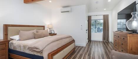 A bedroom with a wooden bed, a nightstand, a dresser, and a lamp.
