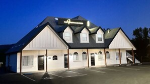 Un edificio de dos pisos con un letrero que dice “The Inn at the Park”. Presenta una fachada simétrica con una entrada central flanqueada por ventanas, y un estacionamiento al frente.