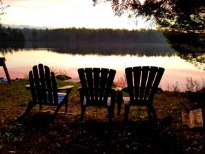 Three Adirondack chairs facing a calm lake with a forested shoreline in the background. - The Birches - Large 3 Bedroom Cottage on Torsey Lake, Mount Vernon ME (Mount Vernon)