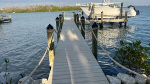 Une jetée en bois menant à un bateau, entourée d’une eau calme et d’une végétation luxuriante.