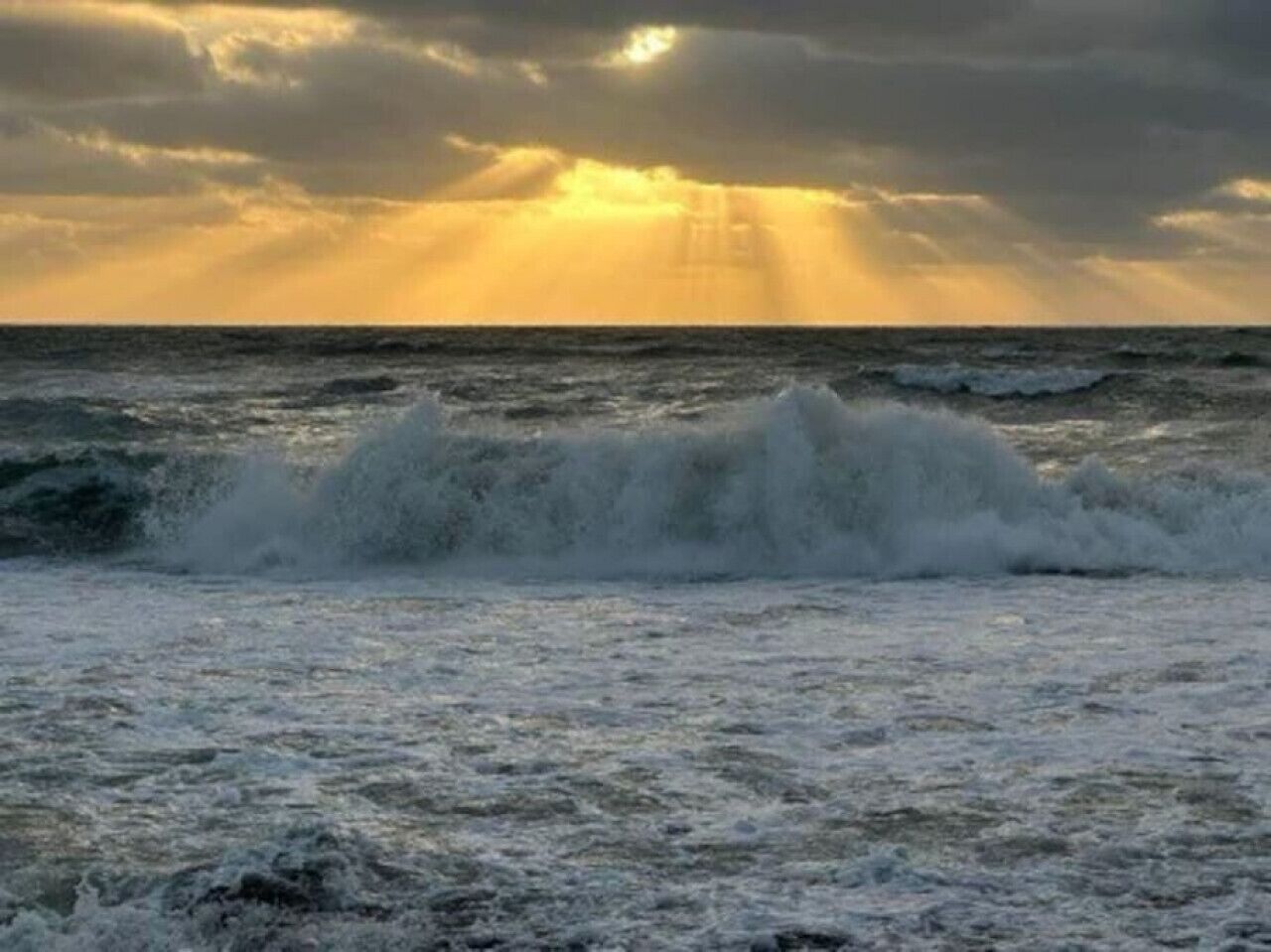 Een woelige zee met golven die op het strand breken.
