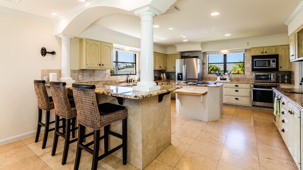 A spacious kitchen with a large island, bar stools, and modern appliances.