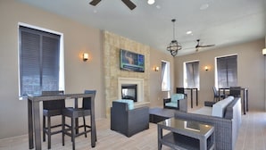 A spacious indoor patio area with wicker furniture, a fireplace, and a television mounted on the wall. - Beautiful Town Home with Splash Pool-8916SA (Kissimmee)