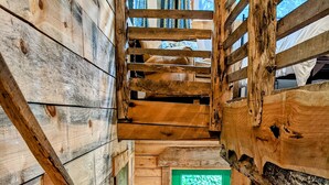 Un escalier en bois mène à une pièce dotée d’une porte verte et d’une fenêtre donnant sur un paysage verdoyant.