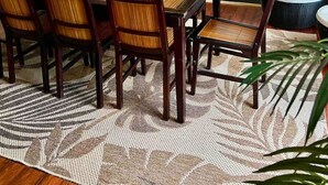 Un comedor amplio con una mesa y sillas de madera, un tapete estampado y un ventilador de techo.