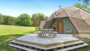 A geodesic dome structure with a wooden deck and picnic table.
