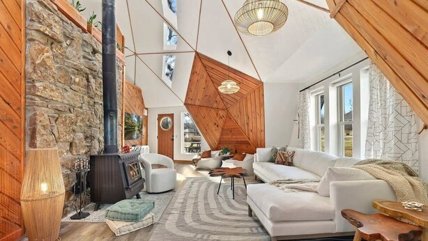 A cozy living room with a stone wall, a fireplace, a white sofa, and a hanging light fixture.