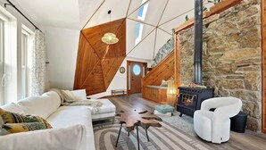 A spacious living area with a white sofa, a unique wooden coffee table, and a stone fireplace.