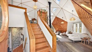 A modern interior with a wooden staircase, a white sofa, and a geometric ceiling design.