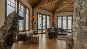 A spacious living room with large windows, a stone wall, and a wooden ceiling. - Experience Luxury in Nature: Private Lodge & Guest Home in Paradise Valley (Emigrant)