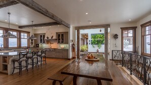 A spacious kitchen with a large island, wooden bar stools, and a rustic dining table. - Experience Luxury in Nature: Private Lodge & Guest Home in Paradise Valley (Emigrant)