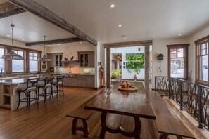 A spacious kitchen with a large island, wooden bar stools, and a rustic dining table.