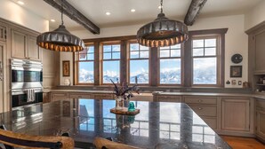 A spacious kitchen with a large island, wooden cabinets, and a view of mountains through large windows. - Experience Luxury in Nature: Private Lodge & Guest Home in Paradise Valley (Emigrant)
