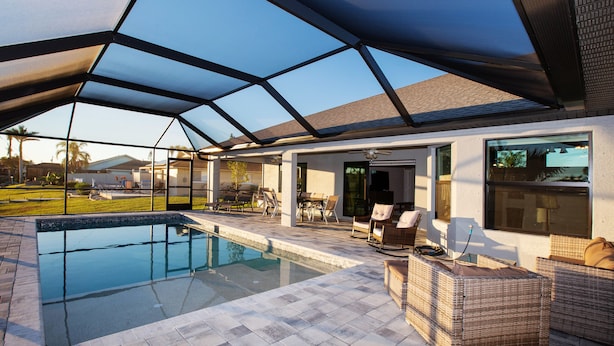 A swimming pool with a covered patio area, outdoor furniture, and a view of the surrounding landscape. - Gulf Access Getaway: Sleeps 10, Private Pool & Boat Rental Option. (Cape Coral)