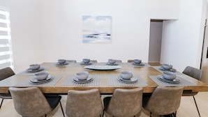 A dining area with a wooden table set for eight, surrounded by six chairs, and a painting on the wall. - Gulf Access Getaway: Sleeps 10, Private Pool & Boat Rental Option. (Cape Coral)