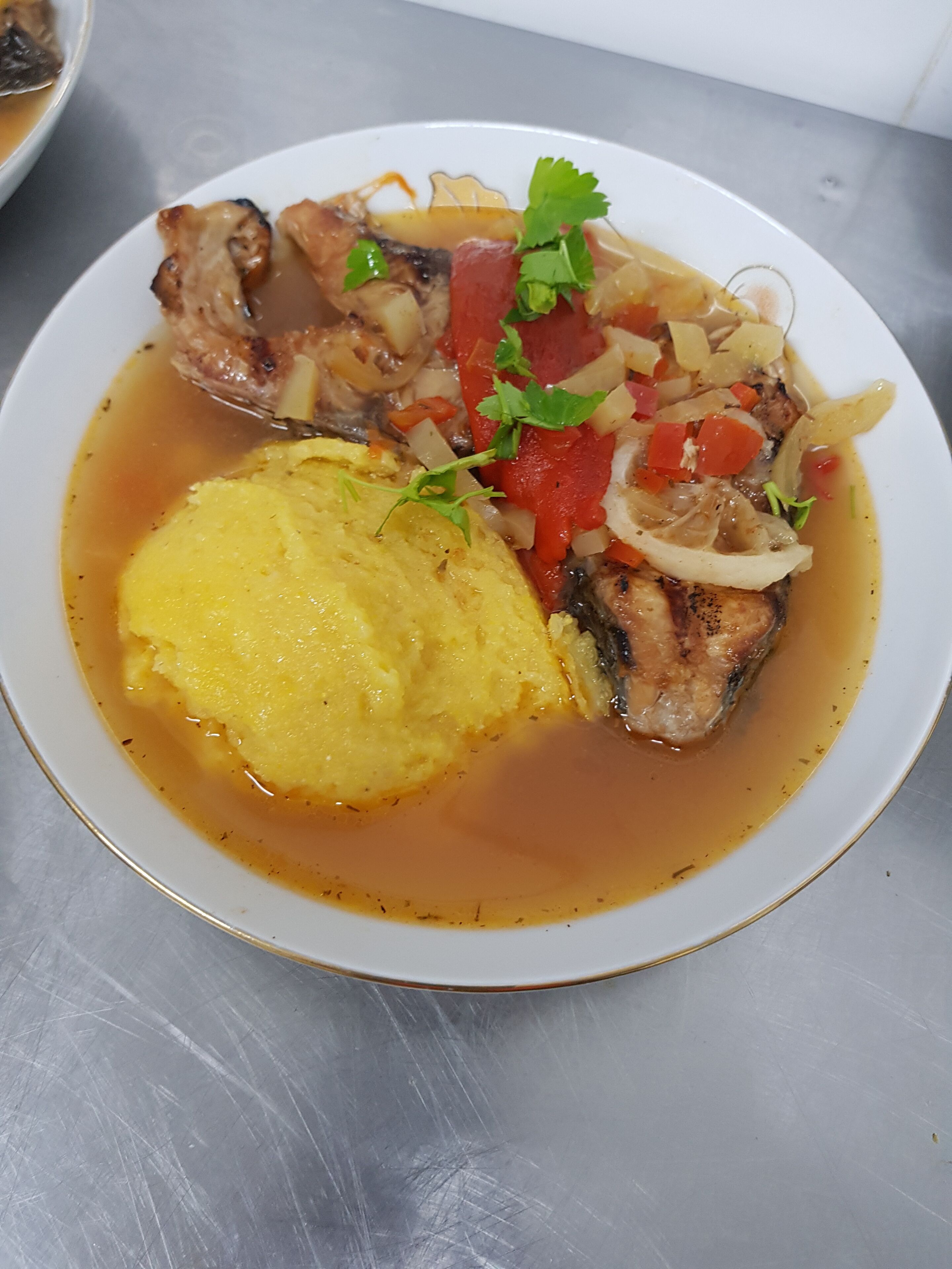 Een bord eten met vis, groenten en een geel bijgerecht.