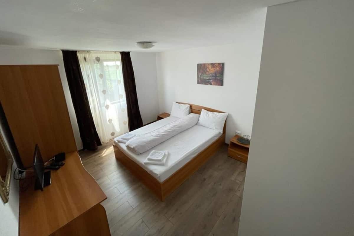A bedroom with a wooden bed, a desk, and a wardrobe.