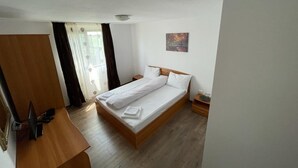 A bedroom with a wooden bed, a desk, and a chair. - Delta crisan flamingo (Crisan)
