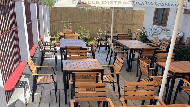 An outdoor dining area with wooden tables and chairs, some with 'URSUS' branding. - Delta crisan flamingo (Crisan)