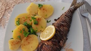 A plate with grilled fish, boiled potatoes, and a lemon slice. - Delta crisan flamingo (Crisan)