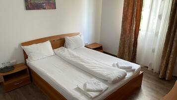 A neatly made bed with white linens and towels, a wooden headboard, and a nightstand with a lamp.