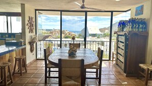Uma sala de jantar com uma mesa redonda, cadeiras e vista para a paisagem urbana através de grandes janelas.