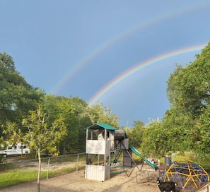 Children can play safely in this secure outdoor playground surrounded by trees and a fence.