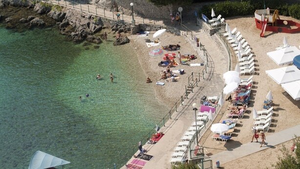 An aerial view of a beach with clear waters, sun loungers, umbrellas, and a lifeguard tower. - Apartment in Ika with Seaview, Balcony, Air condition, WIFI (5025-2) (Ika)