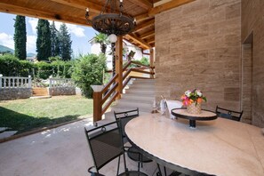 An outdoor patio with a round table, chairs, a chandelier, and a staircase leading to an upper level. - Apartment in Ika with Seaview, Balcony, Air condition, WIFI (5025-2) (Ika)
