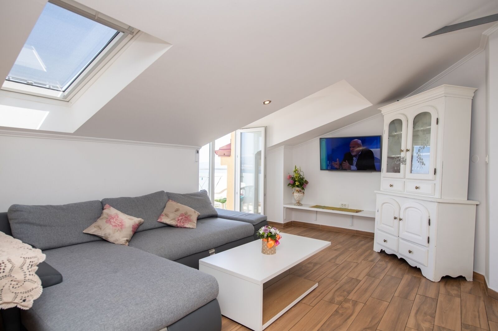 A modern living room with a grey sofa, a white coffee table, and a TV mounted on the wall.