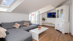 A modern living room with a grey sofa, a white coffee table, and a TV mounted on the wall. - Apartment in Ika with Seaview, Balcony, Air condition, WIFI (5025-2) (Ika)