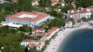 An aerial view of a coastal town with a prominent building with a red roof, a beach with people, and surrounding residential buildings. - Apartment in Ika with Seaview, Balcony, Air condition, WIFI (5025-2) (Ika)