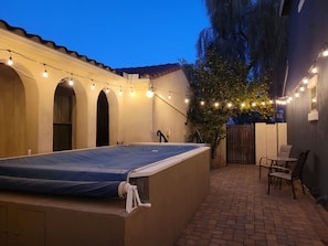 Un espacio al aire libre cubierto con mesa de billar, luces colgantes y un patio de ladrillo.