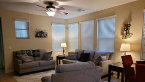 A living room with two sofas, a coffee table, a dining table with chairs, and a ceiling fan.