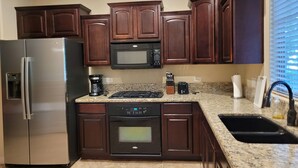 A modern kitchen with dark wood cabinets, stainless steel appliances, granite countertops, and a built-in oven.