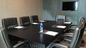 A conference room with a dark wooden table, leather chairs, a water bottle, and a flat-screen TV mounted on the wall. - Cloud Inn River View hotel (Chongqing)