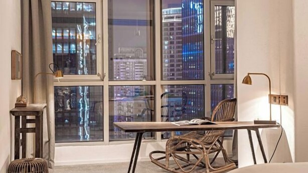 A modern room with a large window, a wooden desk, a rocking chair, and a small side table. - Cloud Inn River View hotel (Chongqing)