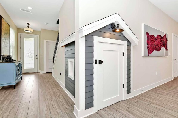 A modern interior with a wooden floor, a white door with a small window, and a red abstract painting on the wall.