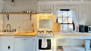A kitchen with white cabinets, a brick backsplash, a gas stove, a dishwasher, and a window with curtains. - Bohemian style open LOFT (Kingston)