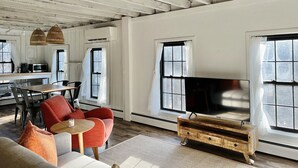 A spacious living room with a large TV, wooden furniture, and a kitchen area with a microwave. - Bohemian style open LOFT (Kingston)