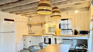 A kitchen with white cabinets, a wooden table, and hanging wicker chandeliers. - Bohemian style open LOFT (Kingston)