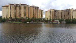 A large, multi-story hotel with a uniform architectural style, situated beside a calm body of water.