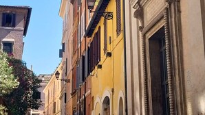 Une rue étroite bordée d’immeubles à l’architecture classique, avec notamment des fenêtres en arc et des moulures décoratives.