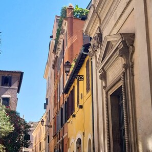Eine schmale Straße mit Gebäuden im klassischen Stil, darunter Rundbogenfenster und dekorative Gesimse.