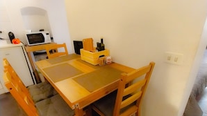 Un petit coin repas avec une table et des chaises en bois, un four à micro-ondes et un réfrigérateur.