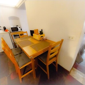 Ein kleiner Essbereich mit einem Holztisch und Stühlen, einer Mikrowelle und einem Kühlschrank.