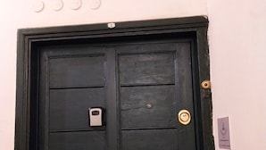 Une porte noire avec un cadenas, une poignée en laiton et un trou de serrure.